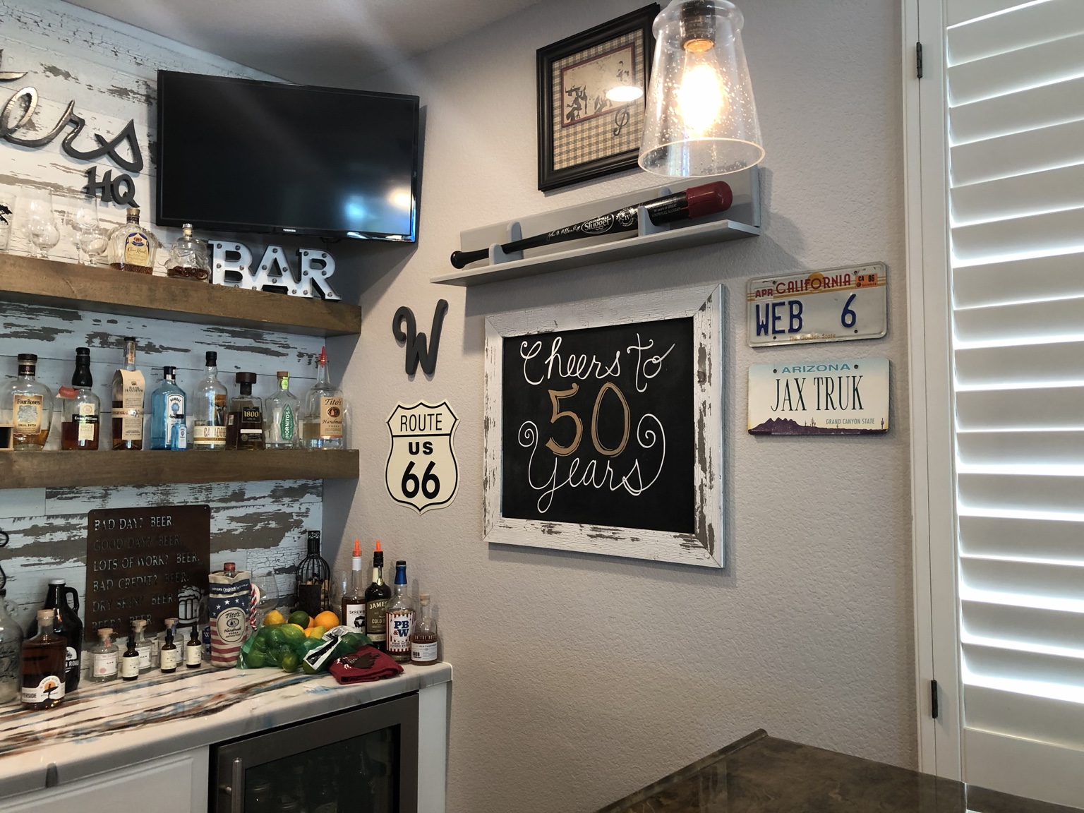 Memorabilia wall with a Cheers to 50 years sign, Route 66 sign, baseball bat and vintage license plates