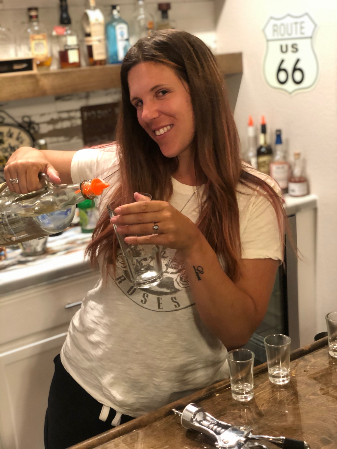 A smiling woman pouring a drink behind the Headquarters bar